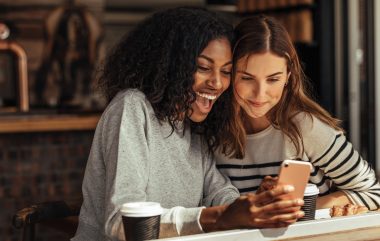 Two,women,sitting,in,a,restaurant,looking,at,mobile,phone
