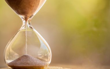 Modern,hourglass,with,green,background, ,sand,trickling,through,the