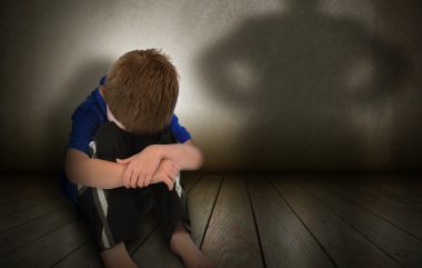 A,young,boy,is,sitting,on,the,ground,and,scared