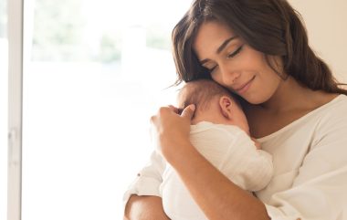 Pretty,woman,holding,a,newborn,baby,in,her,arms