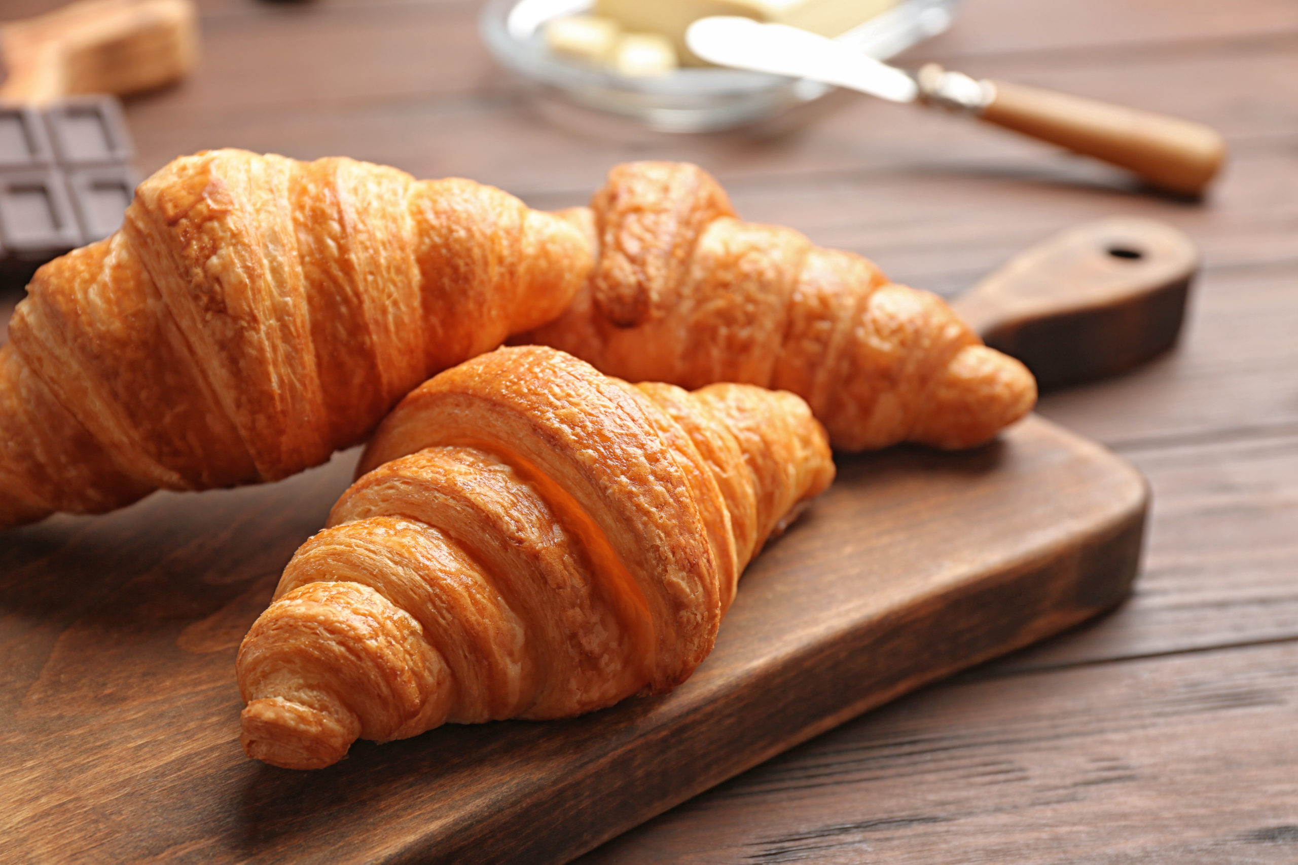 Board,with,tasty,croissants,on,wooden,table,,closeup.,french,pastry